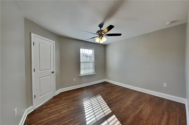 a view of an empty room with window and wooden floor