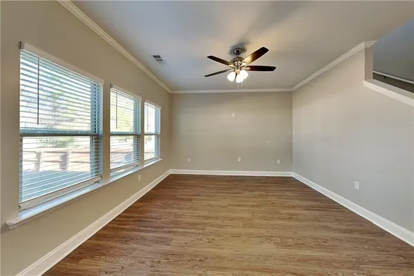 a view of an empty room with a window and wooden floor