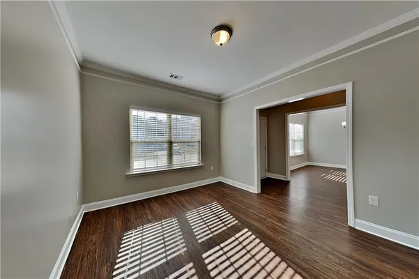 a view of an empty room with glass door and wooden floor