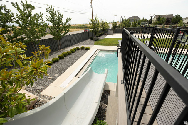 924 Country Lane Farmington, UT 84025 - Photo 65 of 91 Outdoor living area featuring a swimming pool with a slide, an expansive lawn, a patio area, and mature landscaping