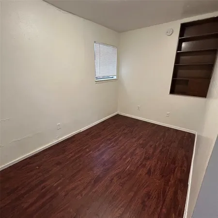 a view of an empty room with wooden floor and windows