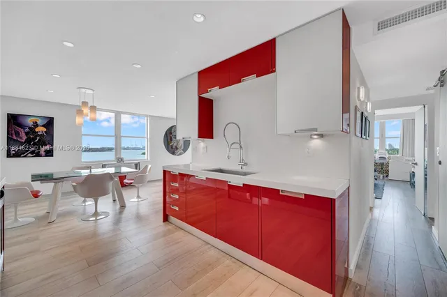 a living room with stainless steel appliances granite countertop a couch a dining table and chairs with wooden floor