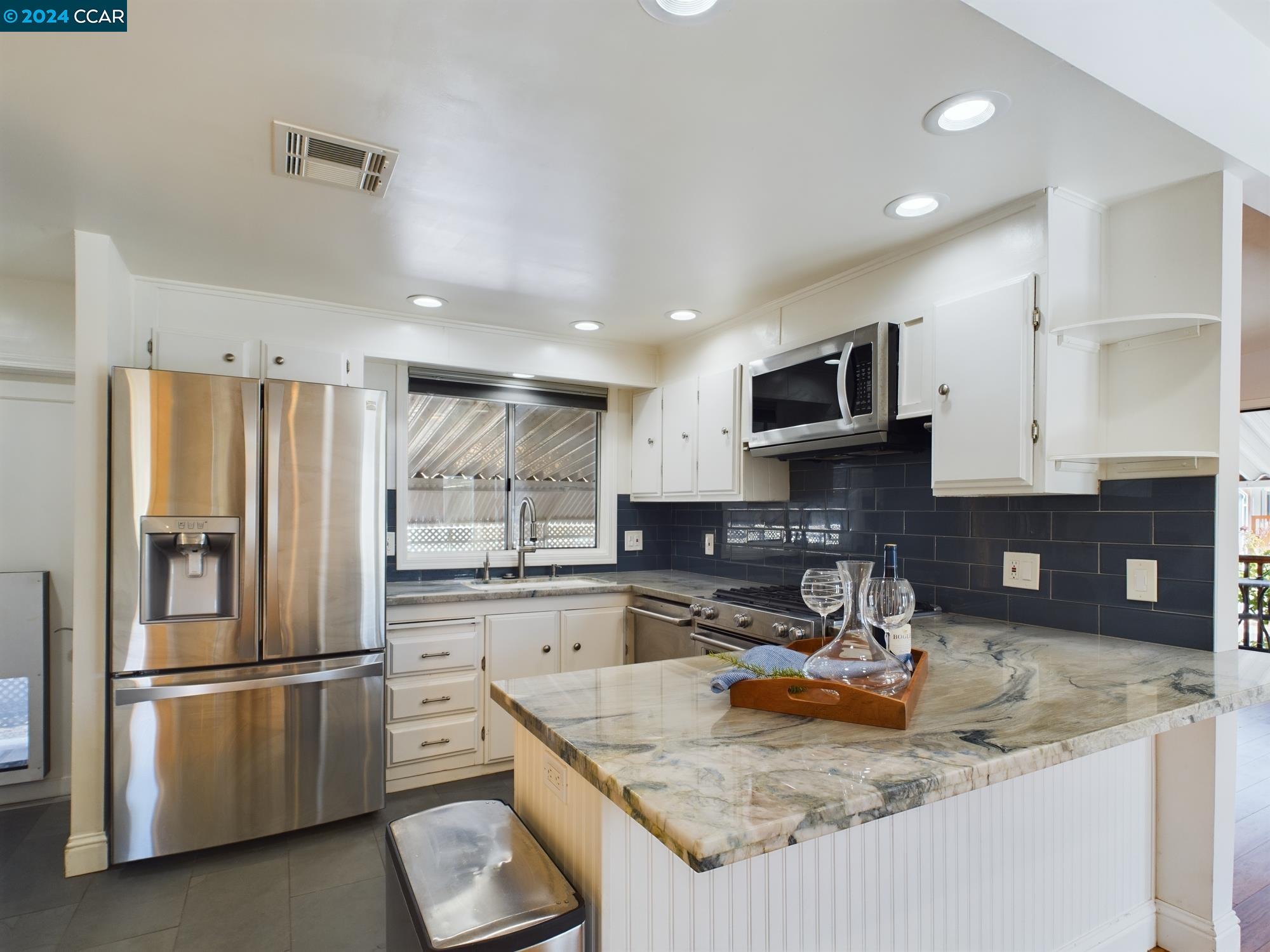 a kitchen with stainless steel appliances granite countertop a refrigerator a stove a sink a microwave and cabinets