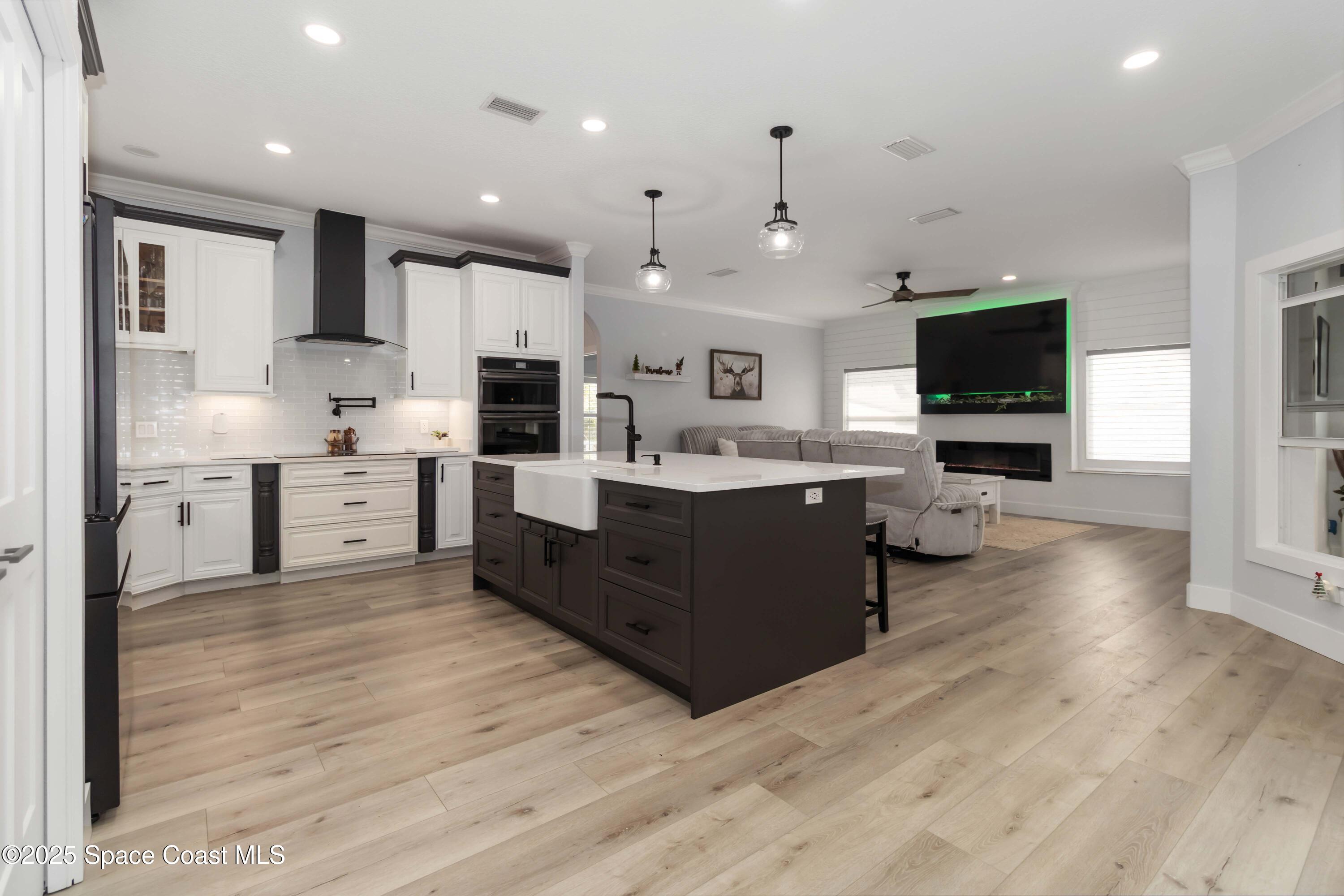 341 Buckskin Street Palm Bay, FL 32909 - Photo 19 of 69 a large kitchen with stainless steel appliances kitchen island granite countertop a stove top oven a sink dishwasher and a refrigerator with wooden floor