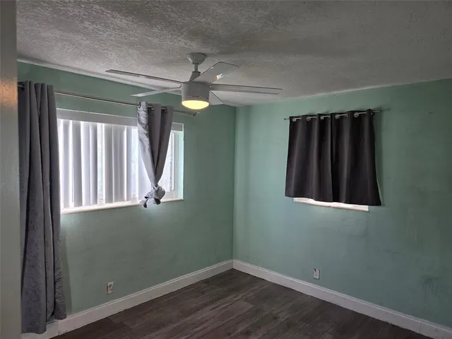 an empty room with wooden floor fan and window