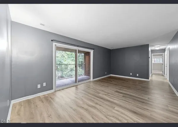 a view of an empty room with window and wooden floor