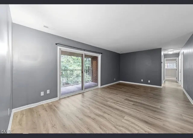 a view of an empty room with window and wooden floor