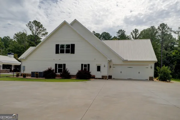 an aerial view of a house with swimming pool and large trees