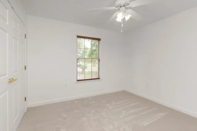 an empty room with a chandelier fan and windows