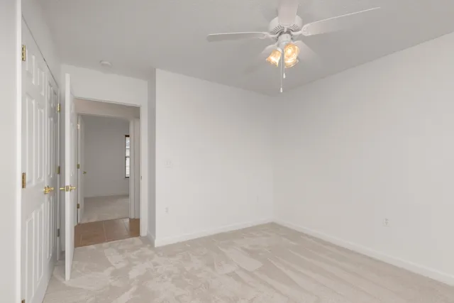 an empty room with a fan and a chandelier fan