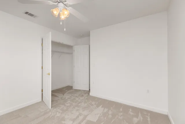 an empty room with a chandelier fan and closet
