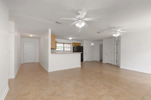 an empty room with a kitchen and a chandelier fan