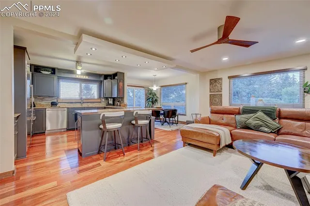 a living room with furniture kitchen view and a large window