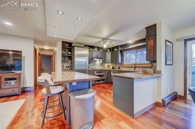 a kitchen with stainless steel appliances kitchen island granite countertop a table chairs in it and wooden floors