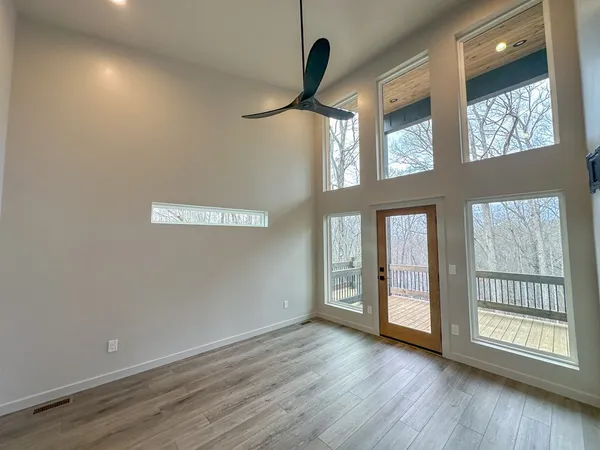 a view of an empty room with a window and wooden floor