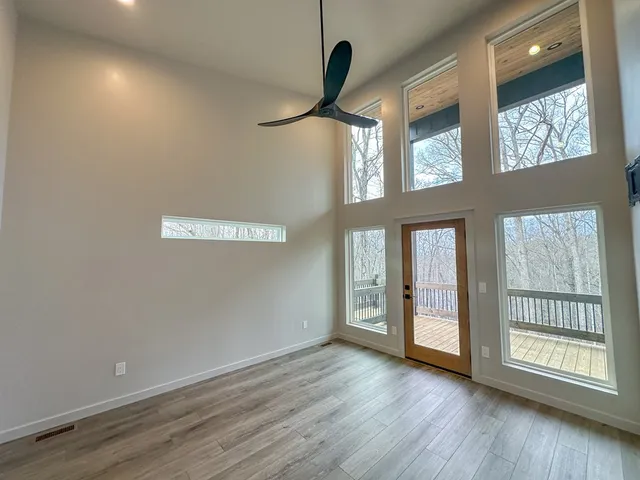 a view of an empty room with a window and wooden floor