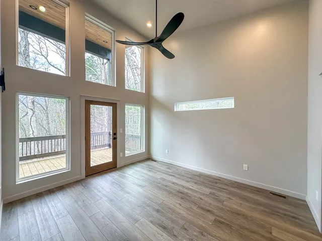 a view of an empty room with a window and wooden floor