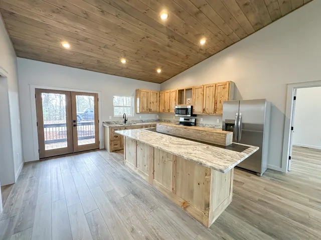 a large kitchen with stainless steel appliances kitchen island granite countertop a large stove a sink dishwasher and a microwave oven with wooden floor