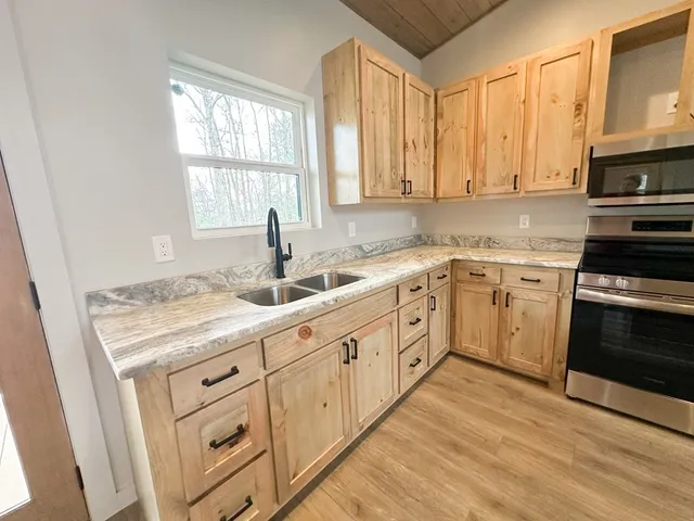 a kitchen with cabinets appliances a sink and a window