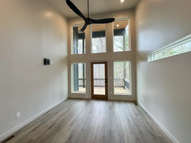 a view of an empty room with wooden floor and a window