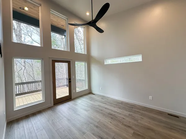 a view of an empty room with a window and wooden floor