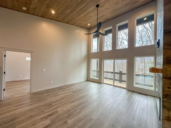 a view of an empty room with a window and wooden floor