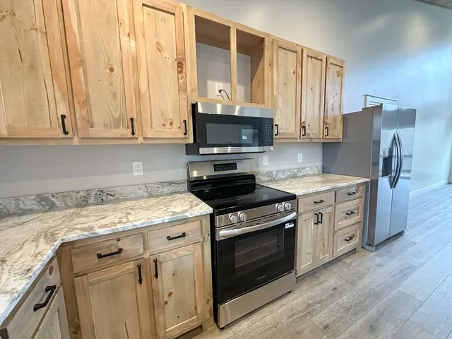 a kitchen with stainless steel appliances granite countertop a stove a sink and a microwave