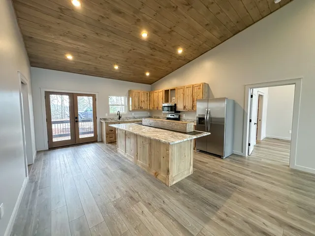 a large kitchen with kitchen island wooden floors white cabinets and stainless steel appliances