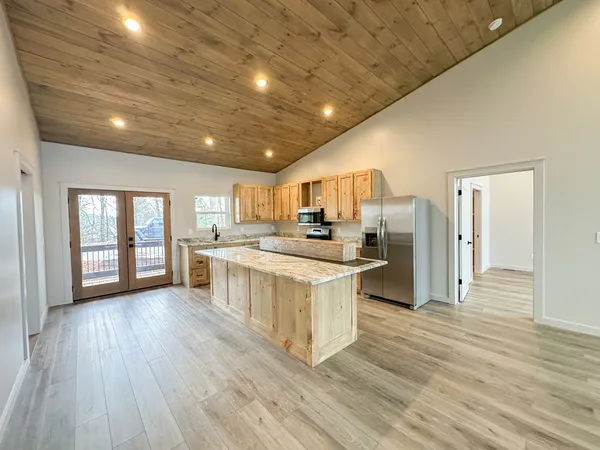a kitchen with stainless steel appliances granite countertop a refrigerator a sink dishwasher a stove and white countertops with wooden floor