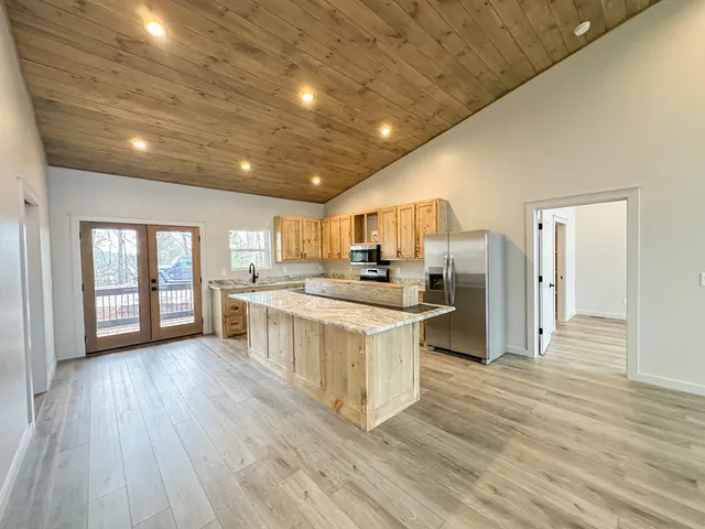 a kitchen with stainless steel appliances granite countertop a refrigerator a sink dishwasher a stove and white countertops with wooden floor