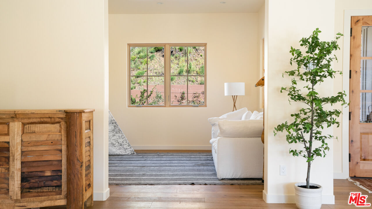 26255 Piuma Road Calabasas, CA 91302 - Photo 12 of 24 a room with a potted plant and a large window with wooden floor