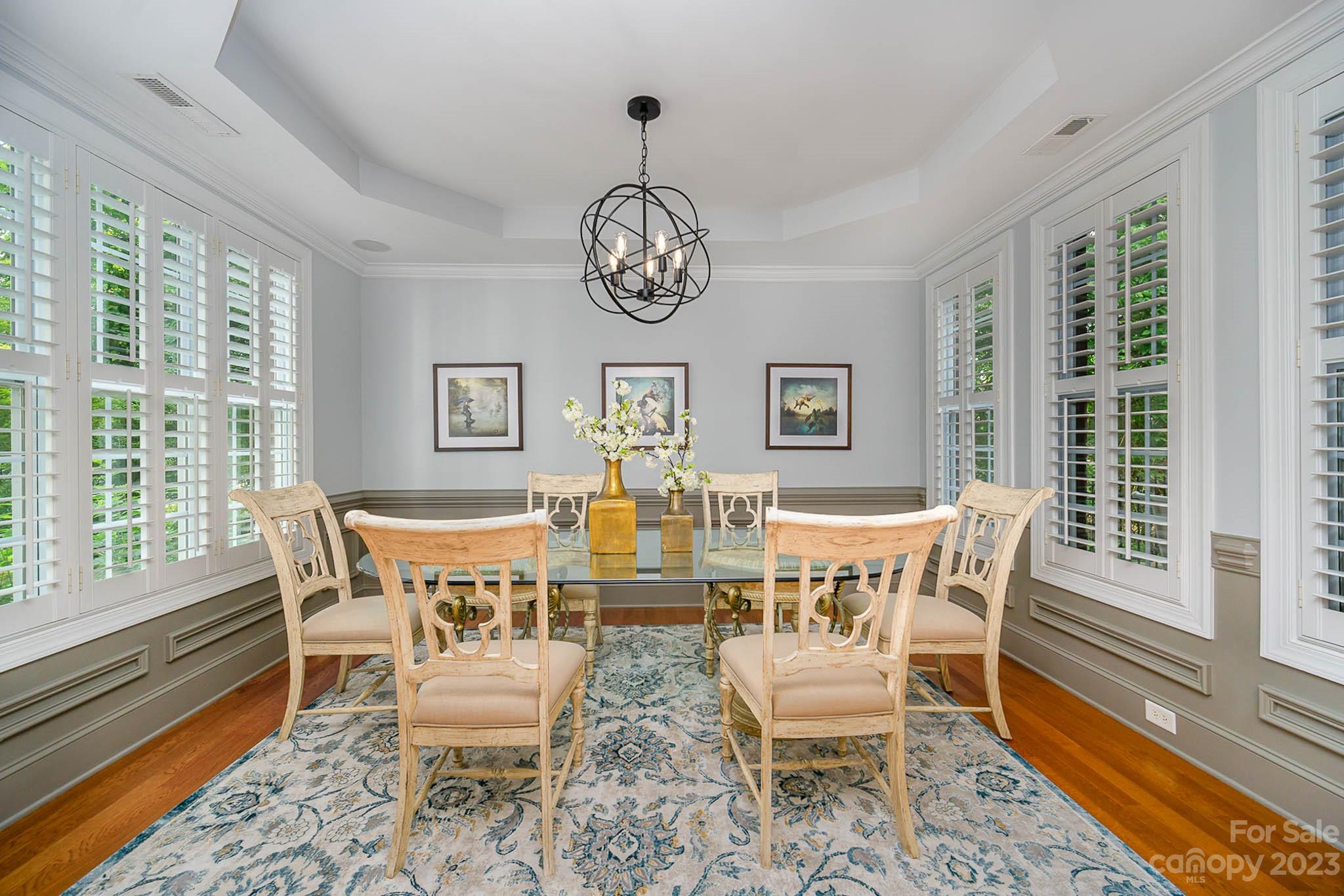 4922 Spur Ranch Road Charlotte, NC 28277 - Photo 4 of 33 a dining room with wooden floor a chandelier a wooden table and chairs