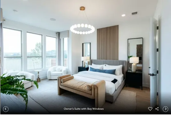 a bedroom with a bed couch and large windows