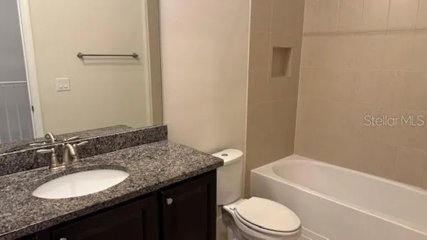 a bathroom with a granite countertop sink toilet a mirror and bathtub