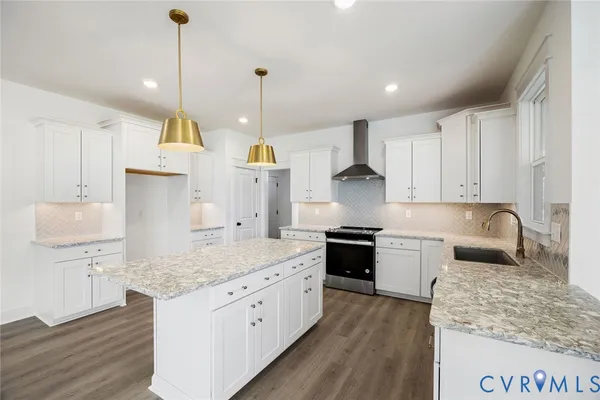 a kitchen with stainless steel appliances granite countertop a sink a stove and a wooden floors