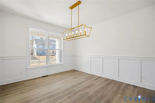 an empty room with wooden floor cabinet and windows