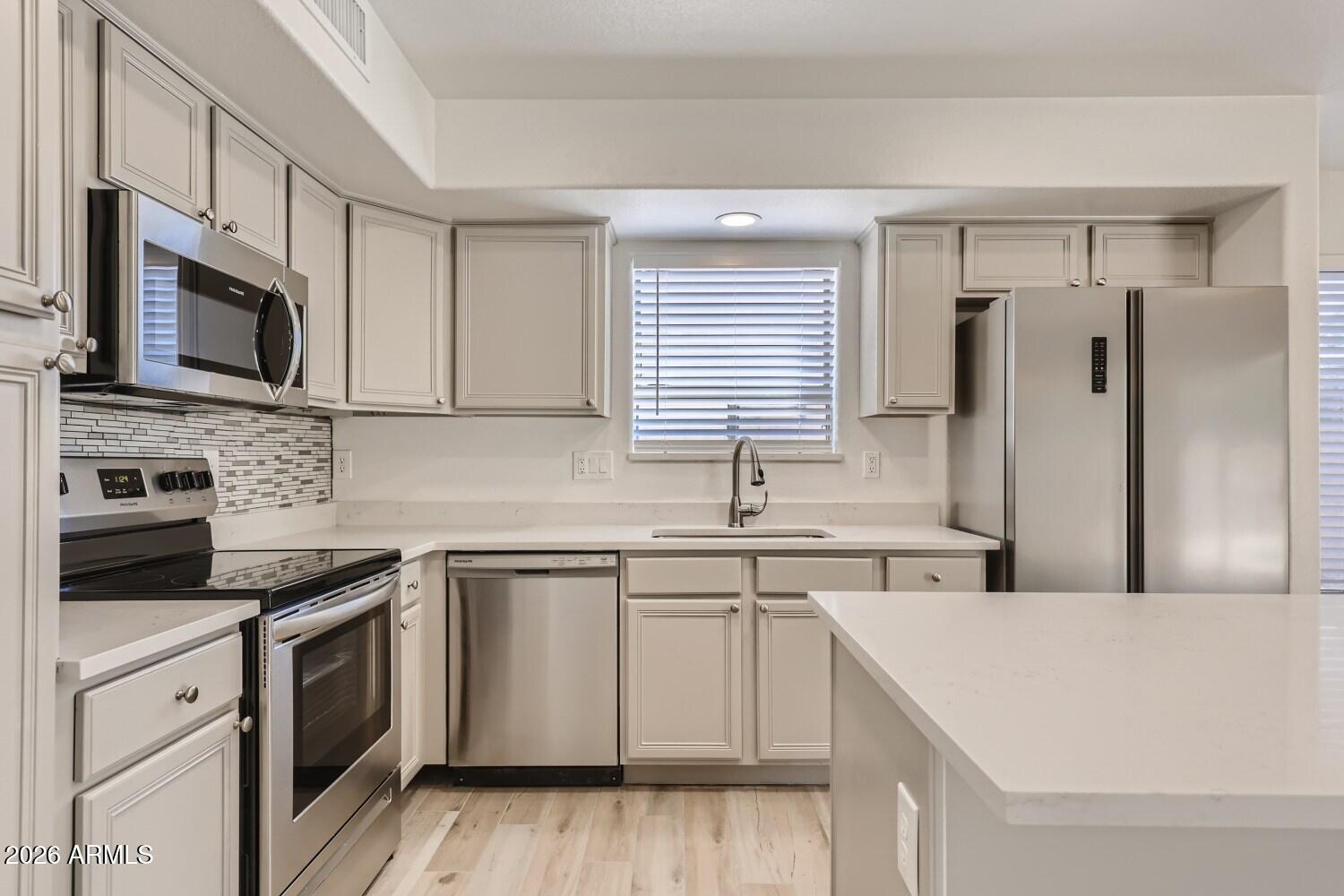 16033 West Diamond Street Goodyear, AZ 85338 - Photo 7 of 28 a kitchen with stainless steel appliances granite countertop a stove top oven a sink dishwasher and a refrigerator with wooden floor