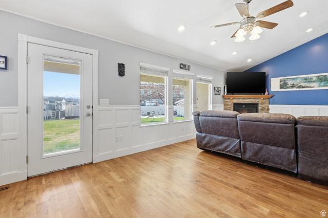 860 West 2980th Street South Logan, UT 84321 - Photo 6 of 38 Living area featuring wood-finish flooring, white wainscoting, and a fireplace with a stone surround