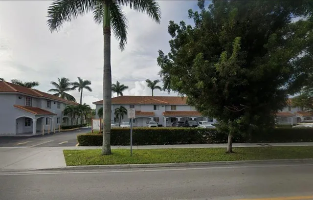 a view of a house with a yard and palm trees