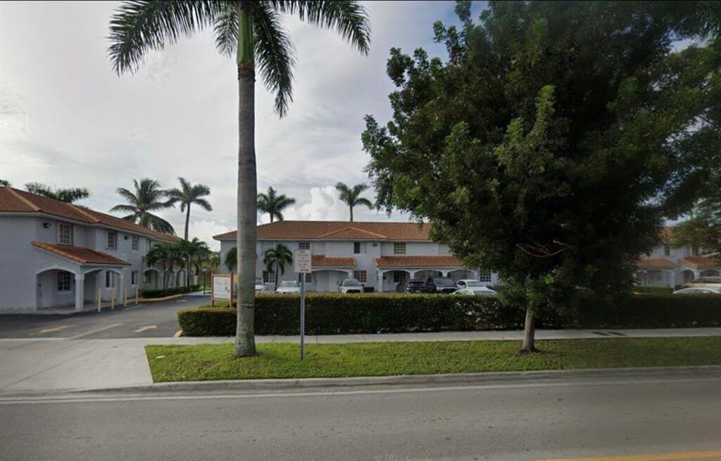 a view of a house with a yard and palm trees