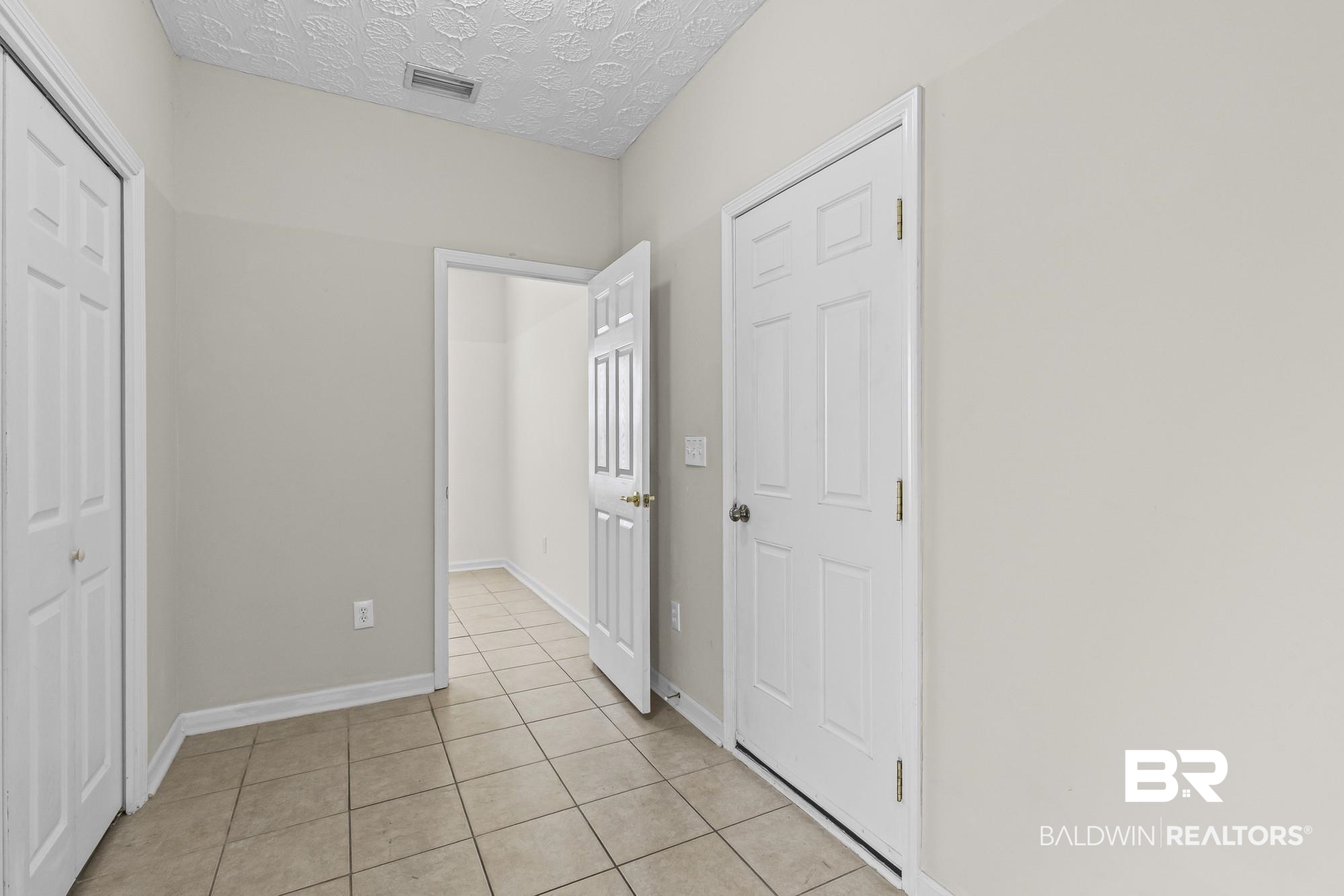 1153 Sloane Cove Foley, AL 36535 - Photo 13 of 25 Unfurnished bedroom with a textured ceiling, light tile patterned flooring, and a closet