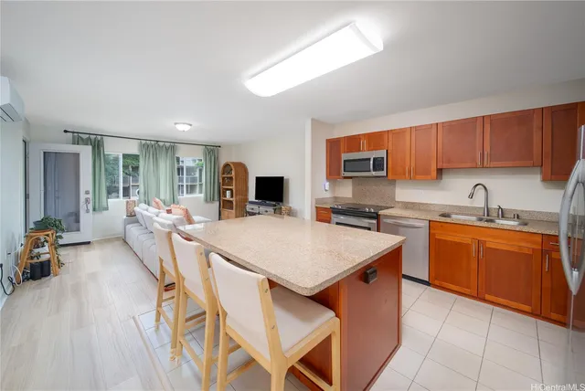 a kitchen with stainless steel appliances granite countertop a sink dishwasher and a refrigerator with wooden floor