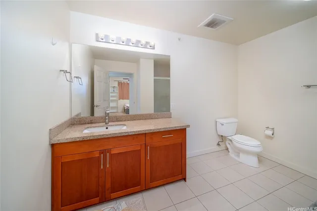 a bathroom with a granite countertop toilet a sink and a mirror
