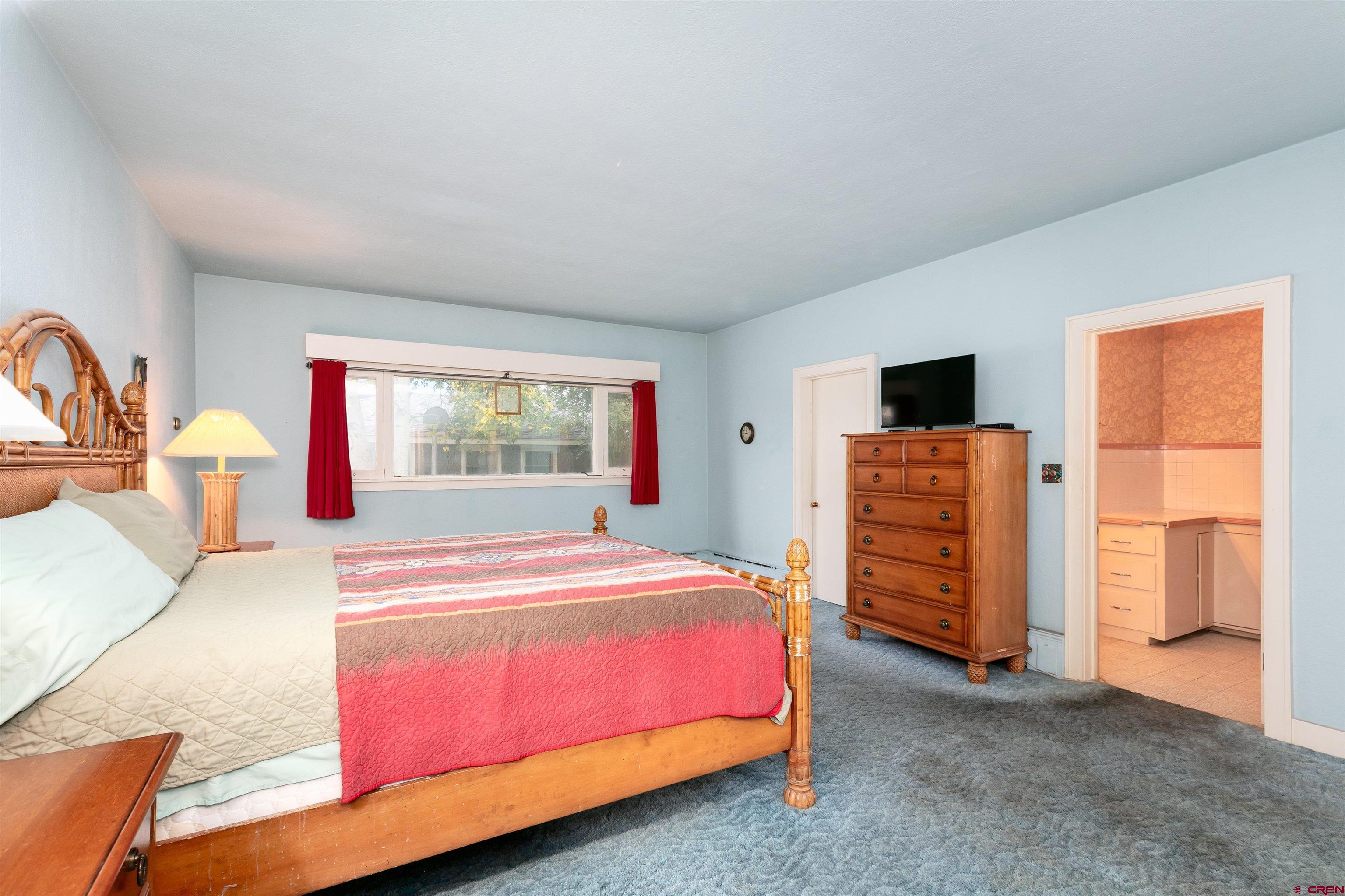 705 Oak Street Del Norte, CO 81132 - Photo 18 of 44 a bedroom with a bed and a flat tv screen on dresser