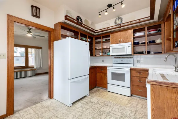 a kitchen with stainless steel appliances granite countertop a refrigerator a stove and a sink with wooden cabinets