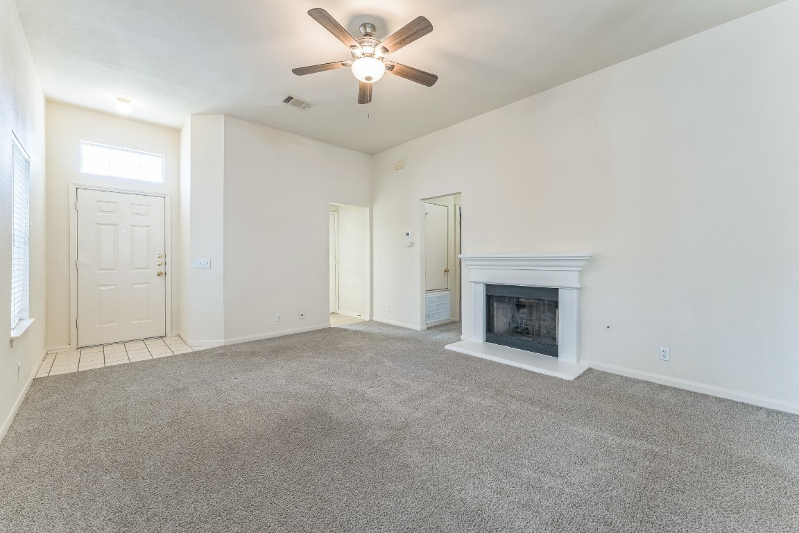 21308 Secretariat Ridge Lane Pflugerville, TX 78660 - Photo 11 of 18 Unfurnished living room featuring carpet, a ceiling fan, and a fireplace with raised hearth
