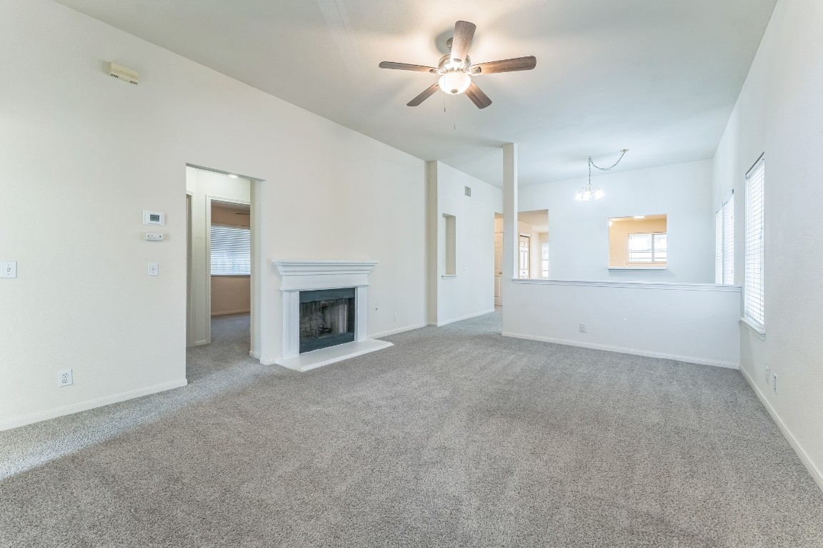 21308 Secretariat Ridge Lane Pflugerville, TX 78660 - Photo 12 of 18 Unfurnished living room featuring carpet floors, ceiling fan, healthy amount of natural light, and a chandelier