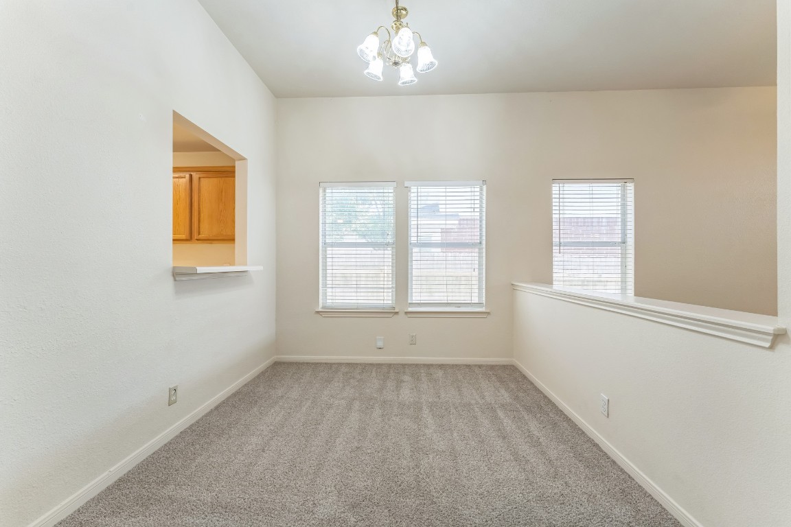 21308 Secretariat Ridge Lane Pflugerville, TX 78660 - Photo 13 of 18 Empty room featuring healthy amount of natural light, light colored carpet, and a chandelier
