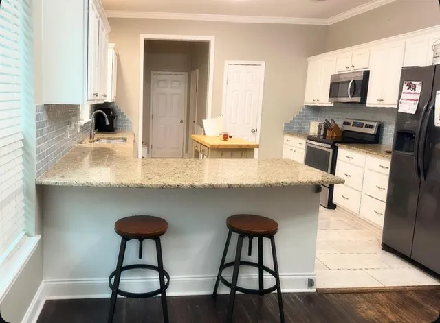 a kitchen with stainless steel appliances granite countertop a sink and a white cabinets