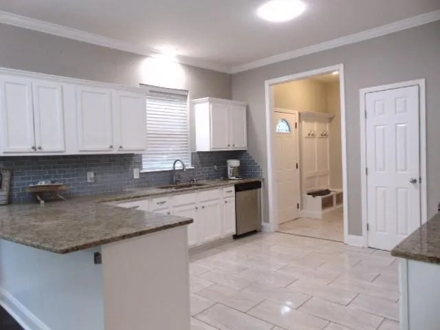 a kitchen with granite countertop a sink a stove and cabinets